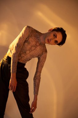 A young queer man with a tattooed body strikes a bold pose against a white background. clipart