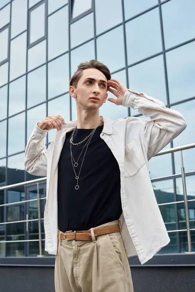 stock image A young queer person exudes confidence in a stylish white shirt and khaki pants, embodying pride and self-expression.