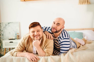 A couple of men enjoy a peaceful moment lounging on top of a bed. clipart