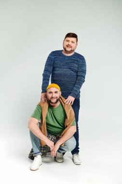 Beyaz bir arka planda iki adam bir anı paylaşıyor..