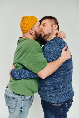 Two men kissing lovingly on white backdrop. clipart