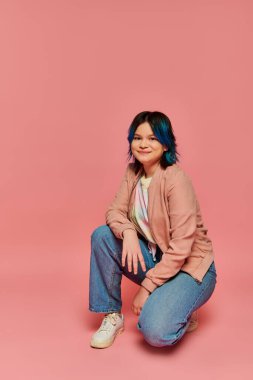 A teen girl with blue hair sits peacefully on a vibrant pink background. clipart