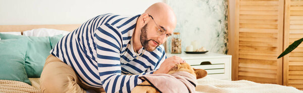A stylish man in striped shirt relaxing on a bed with his dog.