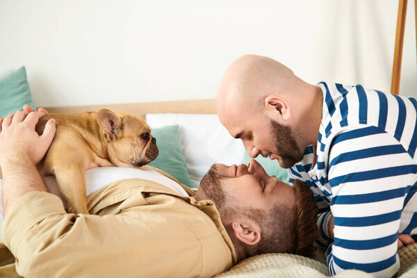 Two men and a dog peacefully lay together on a bed.