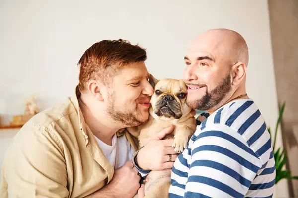 stock image A man lovingly holds a small French Bulldog in his arms, sharing a sweet moment.