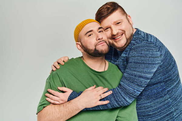 Two men joyfully embrace each other, smiling warmly.