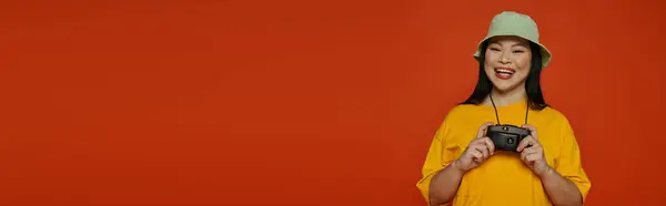 Sarı Tişörtlü Bir Kadın Turuncu Arka Planda Bir Stüdyoda Kamera — Stok fotoğraf