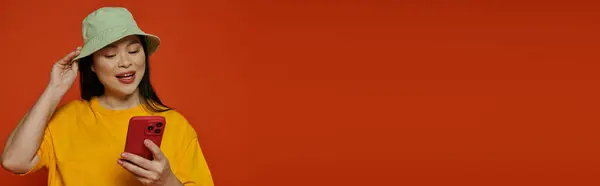 Keltaisessa Paidassa Olevalla Naisella Kännykkä Joka Yhdistää Jonkun Oranssilla Pohjalla tekijänoikeusvapaita kuvapankkikuvia