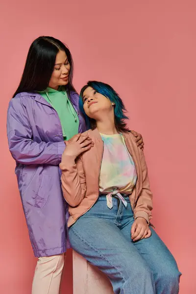 两个女人 一个是亚洲母亲 另一个是十几岁的女儿 她们穿着休闲装站在一起 背景是充满活力的粉色 — 图库照片