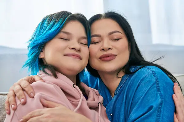 母亲和女儿都是亚洲人 他们在舒适的沙发上分享着舒适的拥抱 表现出爱情和家庭情谊 — 图库照片