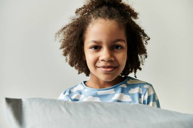 Pijama giymiş genç bir kız yüzünü bir yastığın arkasına saklar ve olay yerine neşe ve neşe getirir..