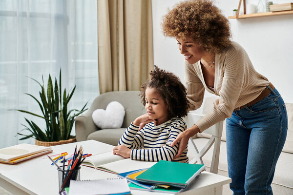 A happy African American mother helping her daughter with homework at home, creating quality time together.