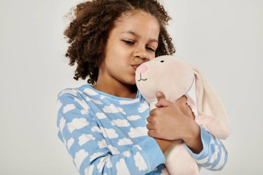 Young girl in pajamas affectionately embraces a stuffed animal clipart