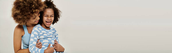 Двое детей нежно обнимаются на белом фоне, демонстрируя чистую и безусловную привязанность..