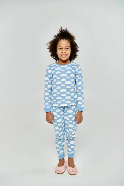 stock image Happy African American mother and daughter in matching blue and white polka dot pajamas against a grey background.