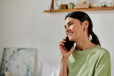 Cep telefonunu kulağına dayayan, evden çalışan bir kadın..
