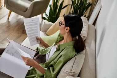 Sıradan bir kadın kanepede huzur içinde kitap okur..