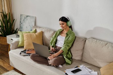 Gündelik kıyafetli bir kadın kanepesinde dizüstü bilgisayarla birden fazla iş yapıyor..