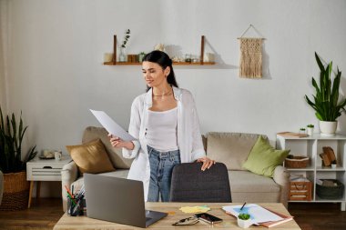 Woman in living room, holding paper. clipart