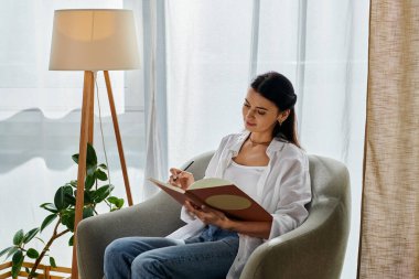 Bir sandalyede otururken kendini kitaba kaptırmış bir kadın..