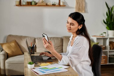 Gündelik kıyafetli bir kadın, masada dizüstü bilgisayarla çalışıyor..