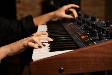 Yetenekli bir kadın, müzik grubu provası için mükemmel bir ahenk yaratan bir müzik stüdyosunda sentezleyici çalıyor..