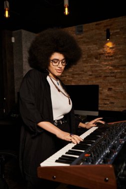 A talented woman with an afro hairstyle plays a keyboard during a music band rehearsal in a recording studio. clipart