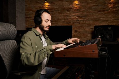 Müzik grubu provası sırasında kulaklık takan bir müzisyen bir stüdyoda klavye çalar..