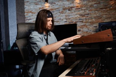 Müzik grubunun provası sırasında bir stüdyoda elektronik klavye çalan bir adam..