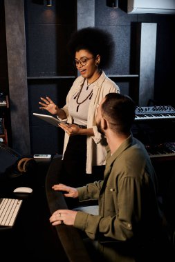 Two individuals from a music band engaging in a discussion within a recording studio setting. clipart