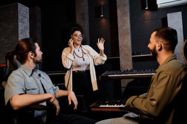 Üç kişi, bir müzik grubu, prova sırasında bir kayıt stüdyosunda iletişim kuruyor..