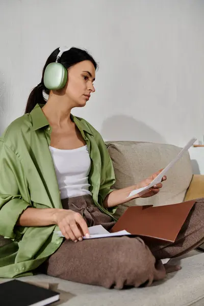 stock image Woman in casual attire enjoys music on a couch with headphones.