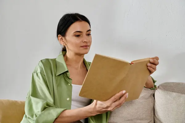 stock image A woman engrossed in a book while sitting on a couch.