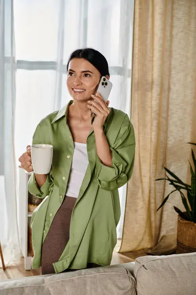 stock image A stylish woman balancing a cup of coffee and a cell phone.