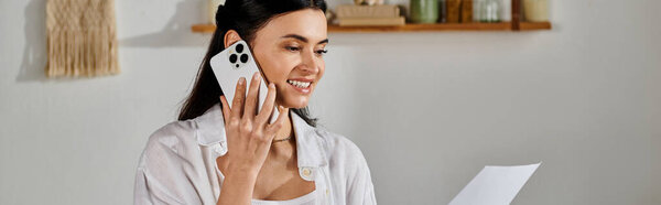 Woman talking on cell phone, holding papers.