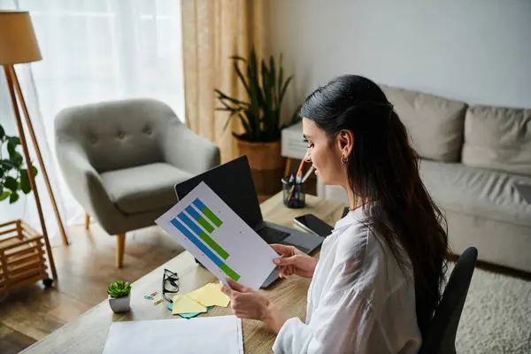 stock image A stylish woman sits at a desk, holding a paper with a look of excitement.