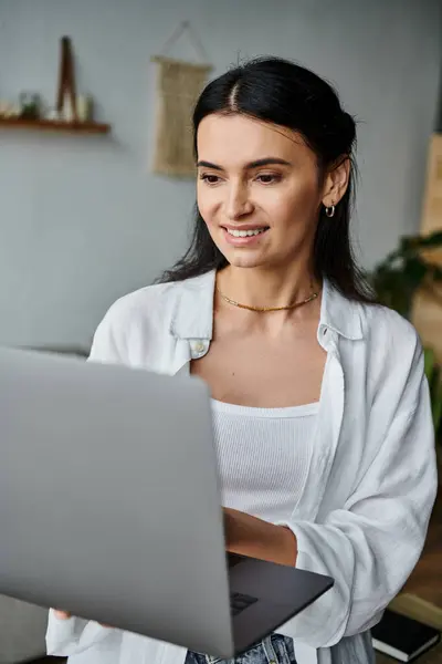 stock image A woman sits at a laptop, focused on her work.