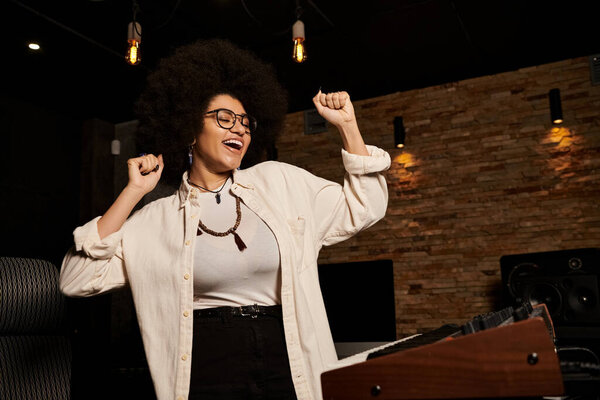 Женщина уверенно стоит в студии звукозаписи, окруженная музыкальным оборудованием и инструментами.