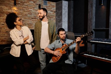 Farklı bir grup insan, tek bir kişinin gitar çaldığı bir kayıt stüdyosunda iş birliği yapıyor..