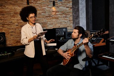 Woman and man collaborate in music band rehearsal within recording studio. clipart