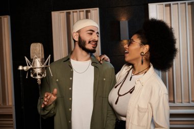 A man and woman stand side by side in a recording studio, immersed in rehearsing for their music band. clipart