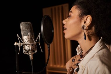 A talented woman passionately sings into a microphone while recording in a music studio with her band. clipart