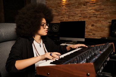 A talented woman plays a keyboard in a recording studio during a music band rehearsal. clipart