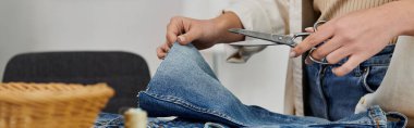 Person cutting jeans with scissors in creative upcycling process. clipart