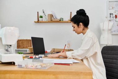 Young woman upcycles clothes, eco-friendly, working on laptop. clipart