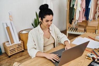 Genç bir kadın laptopunu kullanarak kıyafetlerini değiştiriyor. Çevreye duyarlı bir yaşam tarzını somutlaştırıyor..