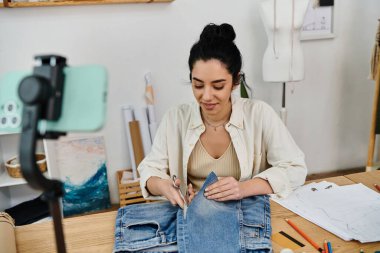 A young woman upcycles her jeans at a table. clipart