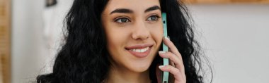 Siyah saçlı genç bir kadın cep telefonuyla konuşuyor..