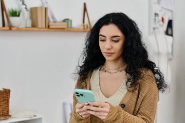 Gündelik giysiler içinde cep telefonunu kullanan genç bir kadın..