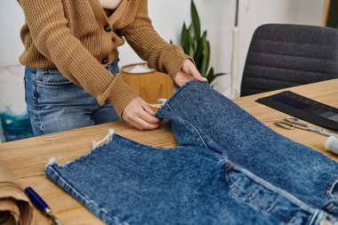 A woman creatively upcycles denim jeans. clipart